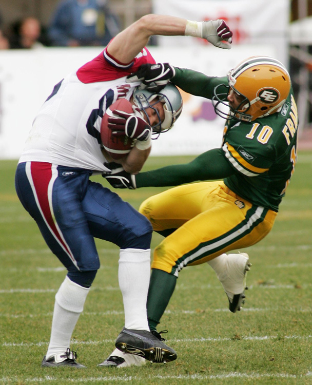 a member of the Edmonton Eskimo football team takes down another player