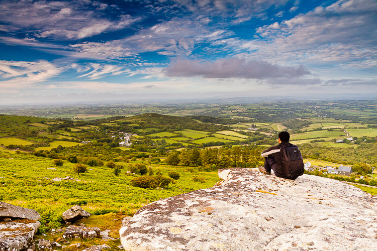 man with a backpack looking at the landscape and valley - beginner photographer tips