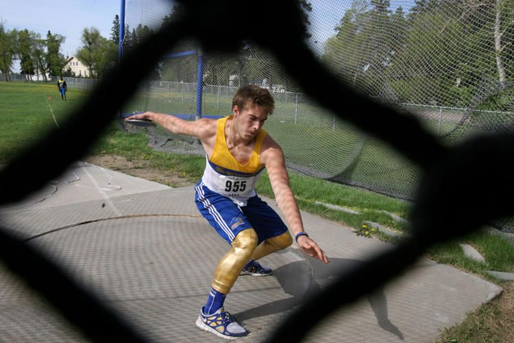 Discus athlete photographed from behind a fence providing a unique angle