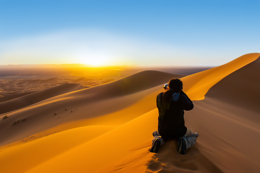 Handsome man with dreadlocks taking a photograph of sunset from a sand dune by Andrea Obzerova on 500px.com