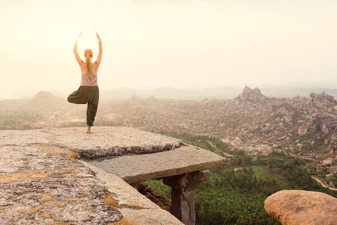 Young woman practicing yoga at mountain cliff on sunrise by Janet Weldon on 500px