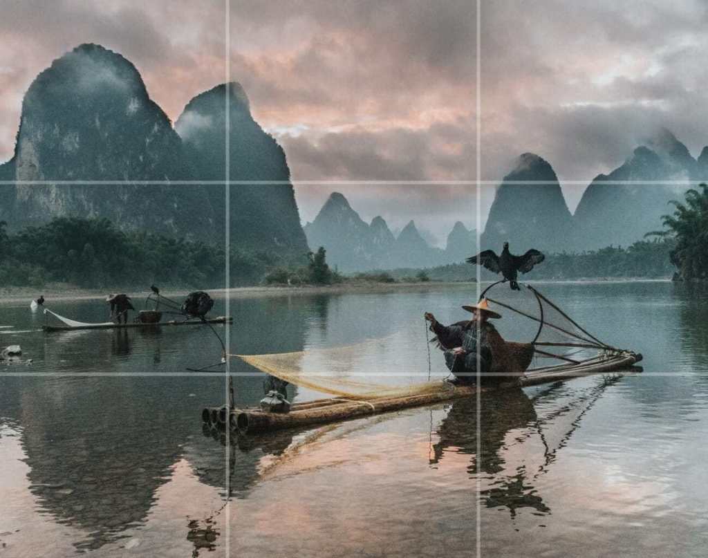 a fisherman in a vietnam lake with a helping bird
