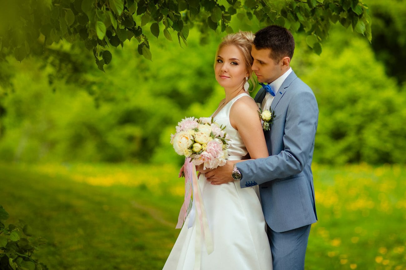 A groom looks at his bride under a tree, demonstrating one of the classic close-up wedding poses