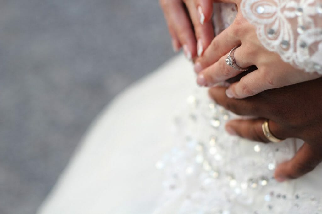 A close-up of a bride and groom's hands and wedding rings