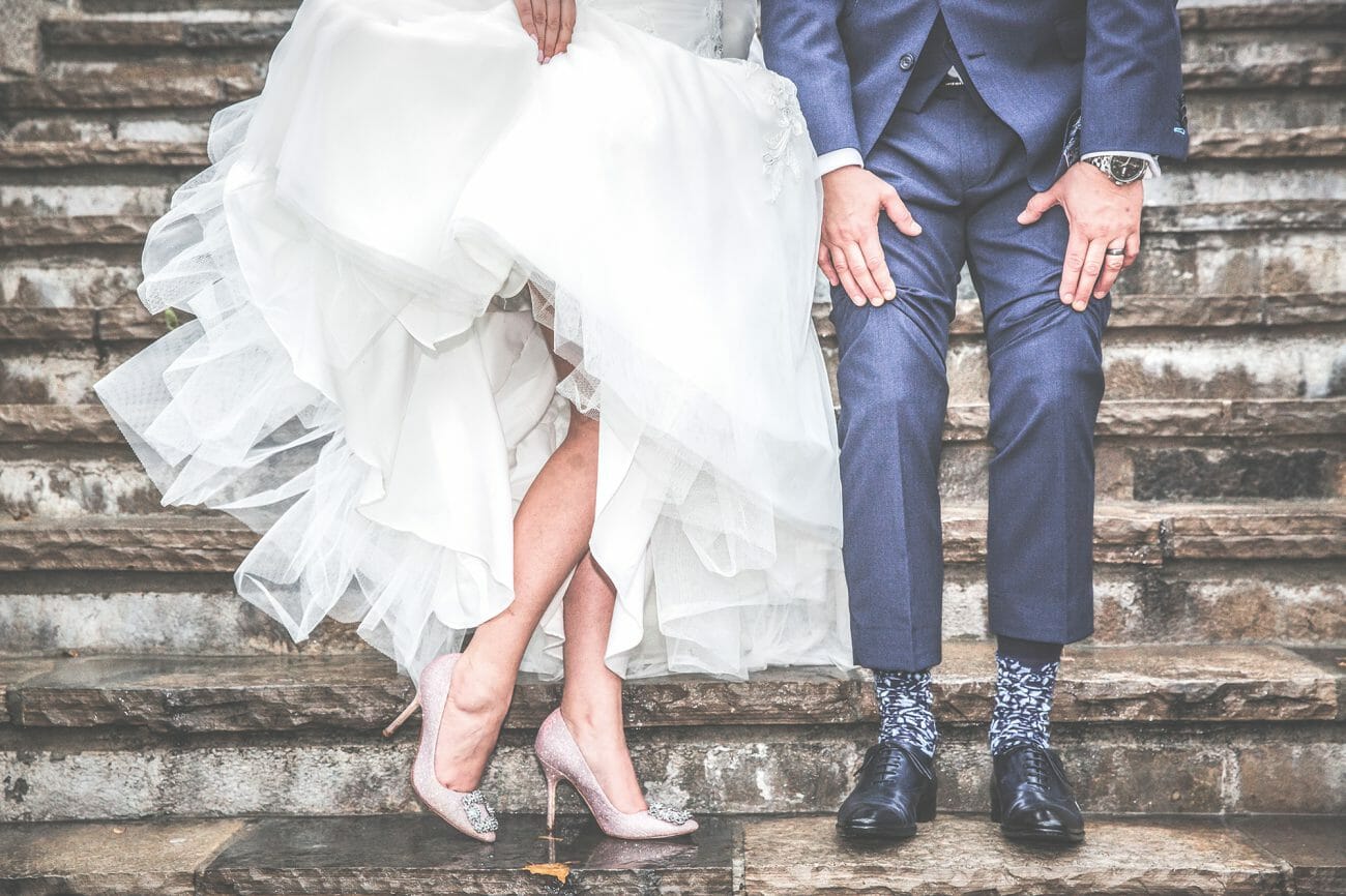 A bride and groom show off their wedding shoes while stood on stone steps, another one of the classic wedding poses