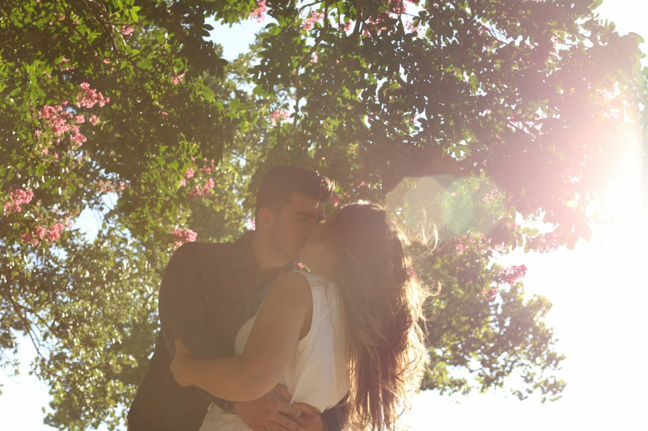 A kissing couple photographed against blooming trees