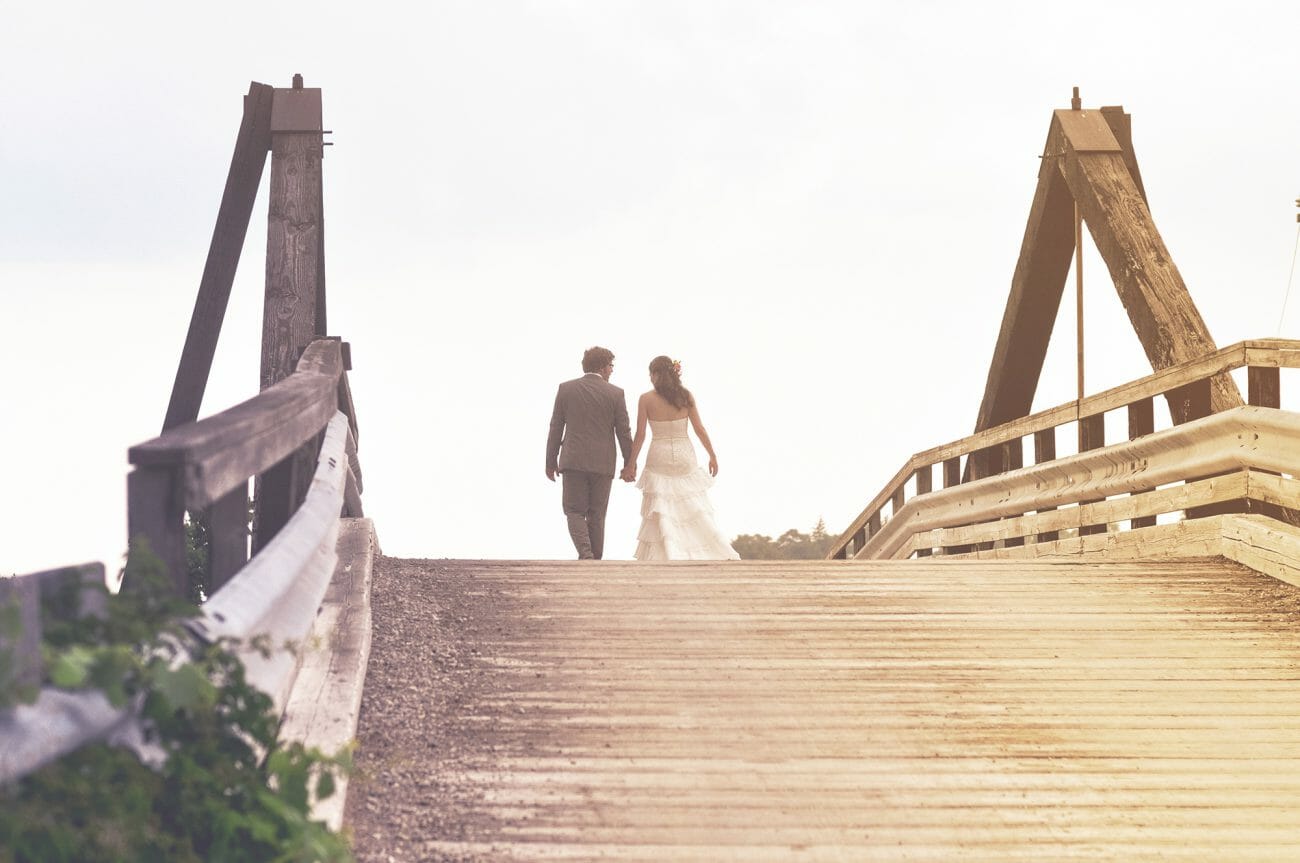 A bridge and groom walk away over a wooden bridge