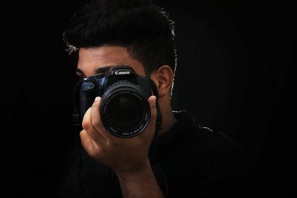 a DSLR photographer looking through the viewfinder to compose a shot.