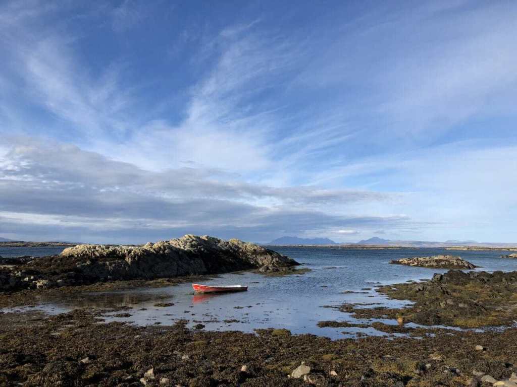 A mobile photography shot of a rowing boat docked in a rocky shore, taken with an iPhone