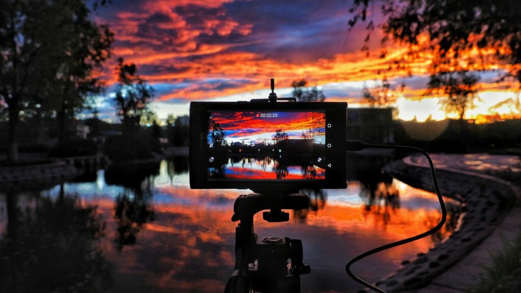 A sunset view over a lake viewed on the screen of a smartphone