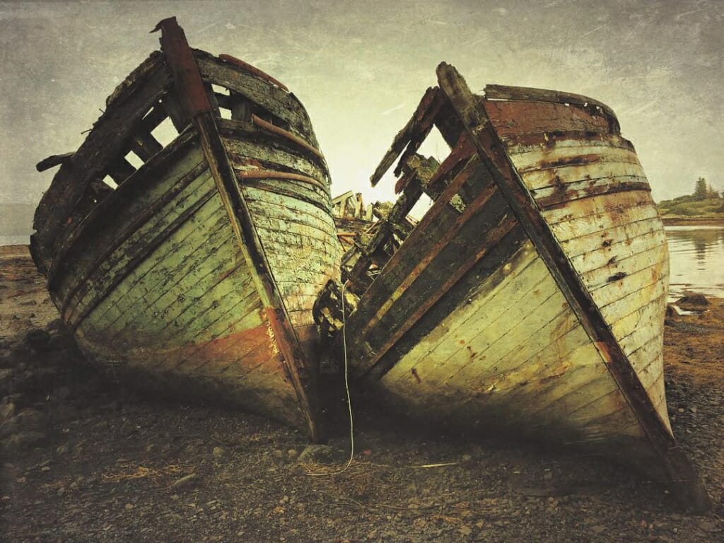 An iPhone photo with a painterly overlay of two disused boats on a shore