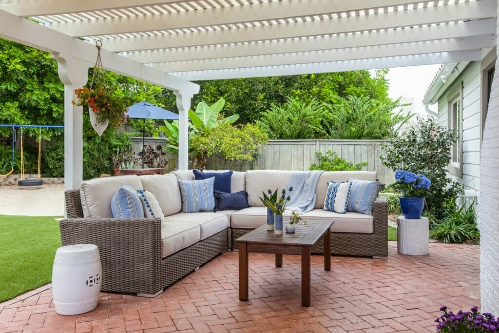 An image of a covered patio area with  a large L-shaped outdoor sofa and coffee table