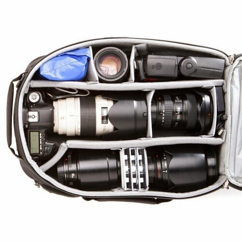 A photo of an open camera bag packed with a camera, lenses and flash