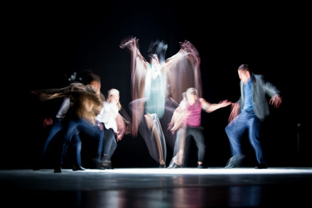 The movements of a group of dancers onstage are emphasized with motion blur