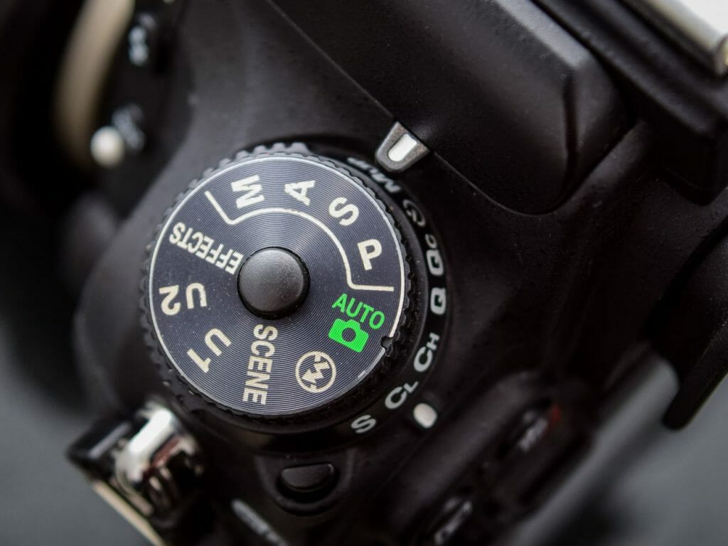 A Nikon camera dial from above set to shutter priority mode