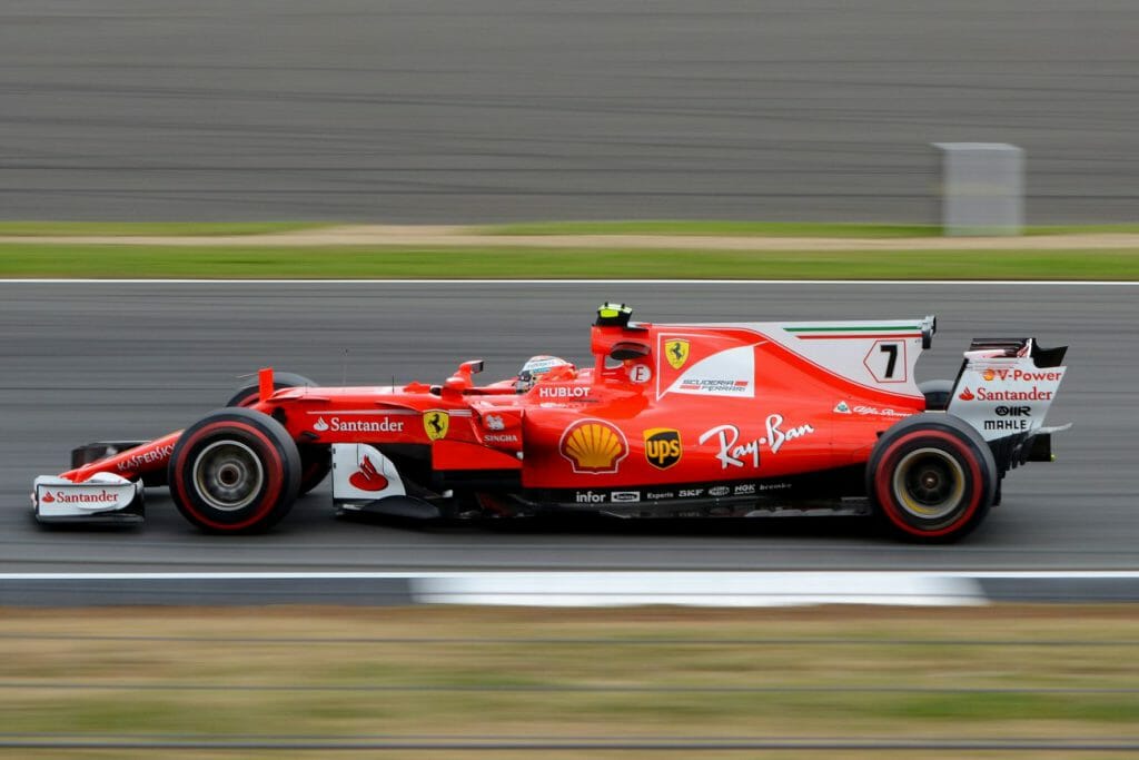 An F1 Ferrari speeds across a race track with motion blur in the background