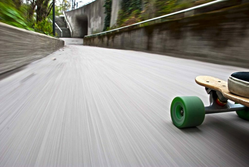 A skateboarder's surroundings blur as he cruises down a hill at speed