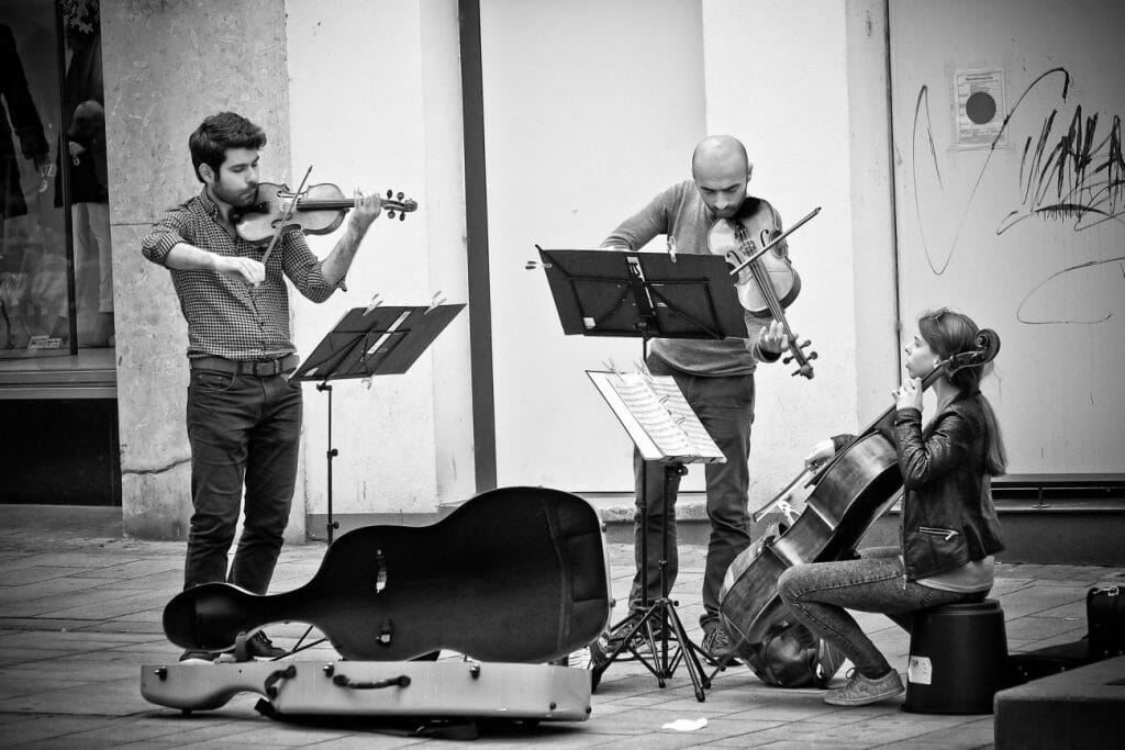 A black and white street image of people playing string instruments