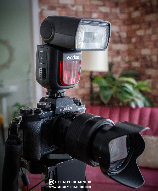 Camera on tripod with a Godox flash on it shown on a Fuji camera