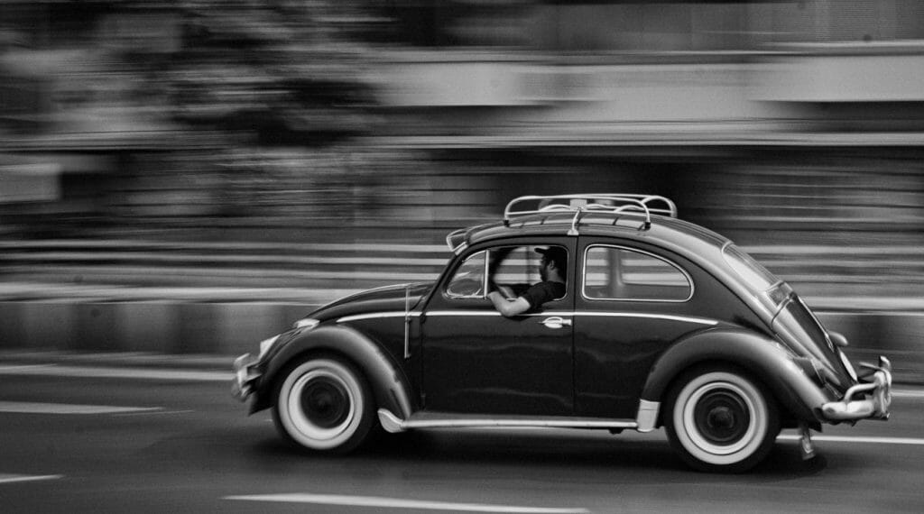 A black and white panning photo of a VW Beetle car in motion