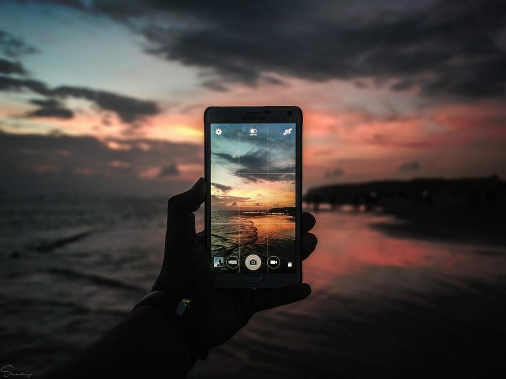 A travel photography shot of a sunset seen through the screen of a smartphone