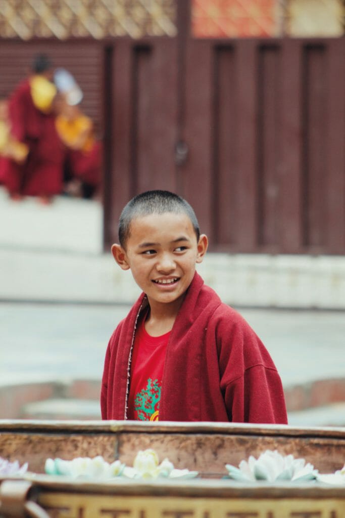 A travel photography image of a young monk in red robes