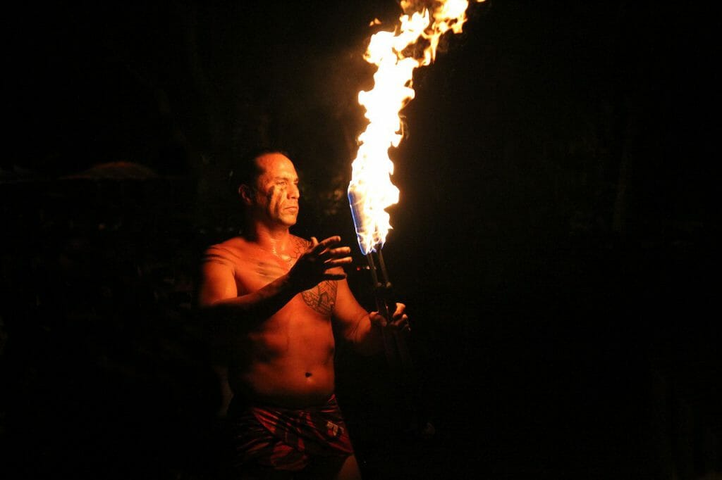 A travel photography image of a Maori man with a flaming torch of fire