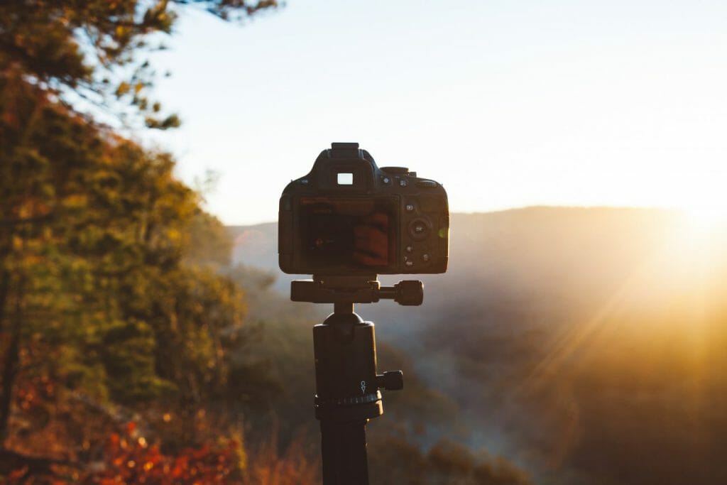 An image of a camera on a tripod in front of a sunset