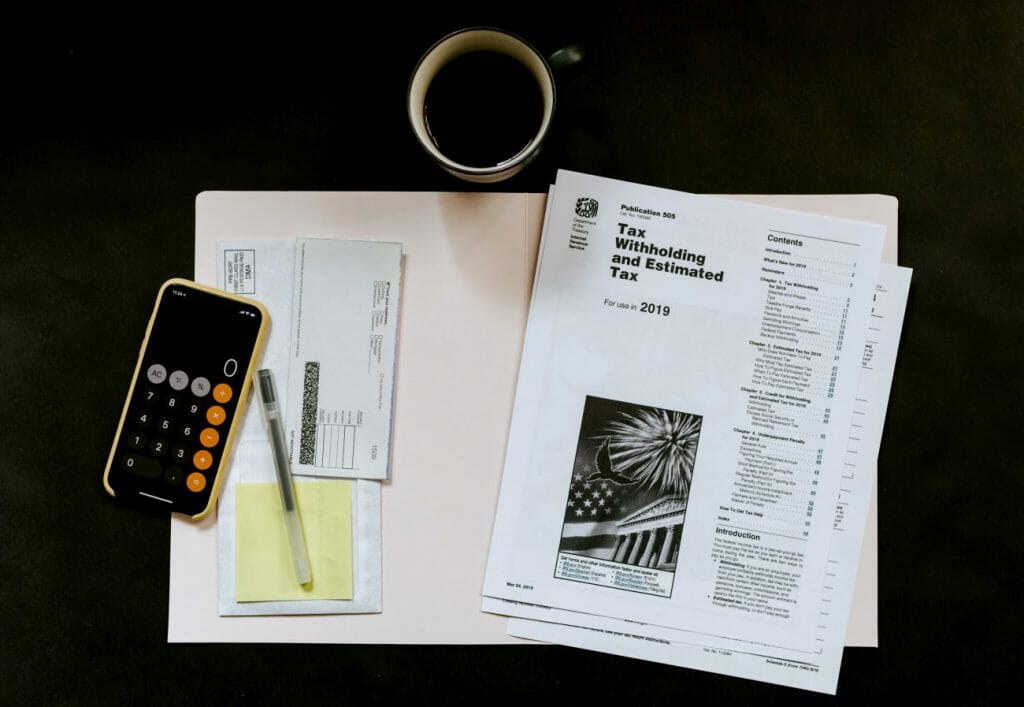 A flat lay view of a black table with an open folder, tax papers and a calculator