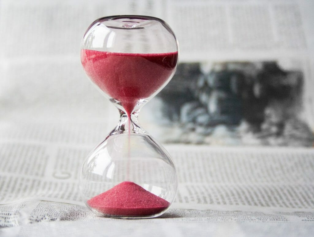 A standing hourglass containing pink on a table
