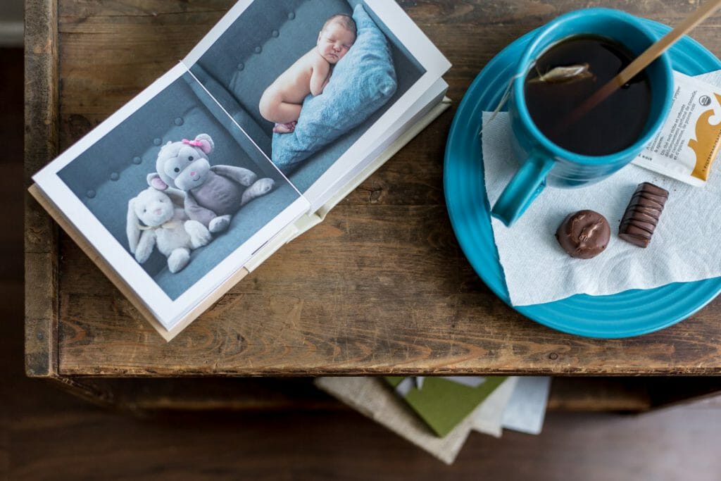 A flat lay view of a table with a baby photo album and cup of tea - another package photography pricing opportunity