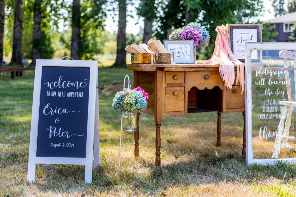 A vintage desk with wedding decor on top and signage standing next to it - photography pricing packages are the industry standard with weddings