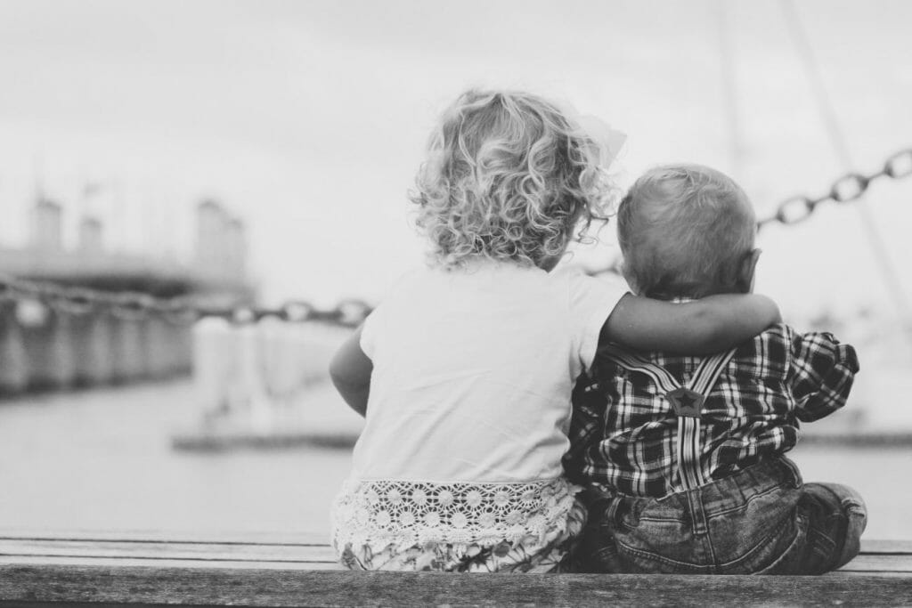 Two family members sitting on a dock while posing for a fmaily photography session.