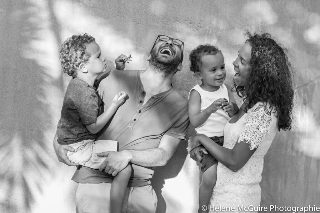 two kids with parents making funny faces while posing for a family portrait photo.