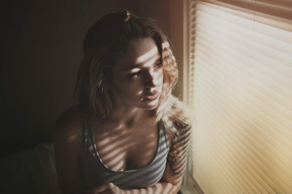 A women sitting by a window with shades on