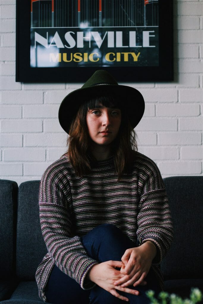 A model sitting facing her side to a window. An example of a moody indoor photography.