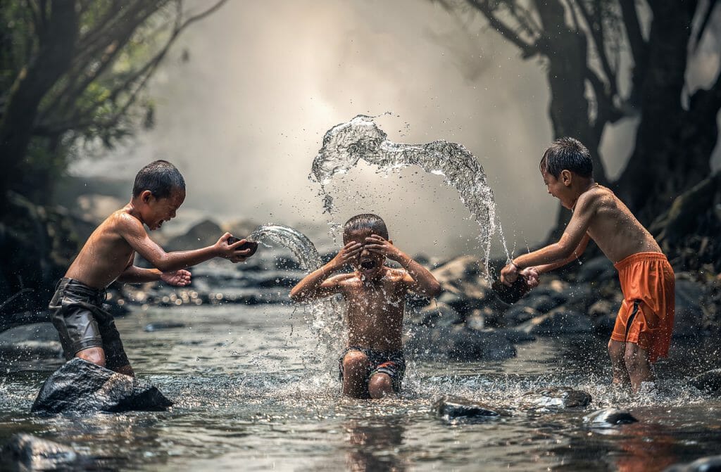 three children playing in water. A kids' photograph captured with a faster shutter speed.