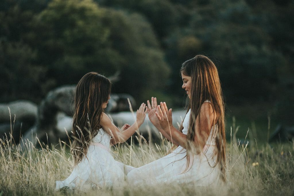 Two kids playing in a field. background is blurry due to large aperture.