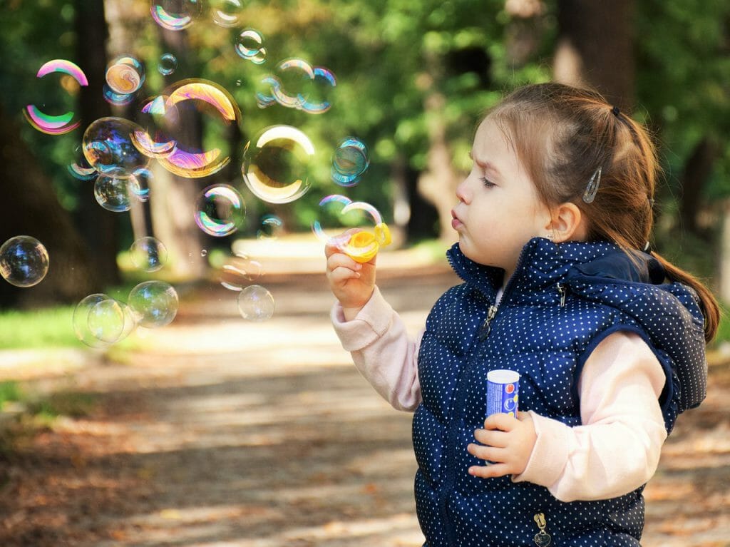 A kid blowing bubbles in a sunny day. Captured with low ISO setting.