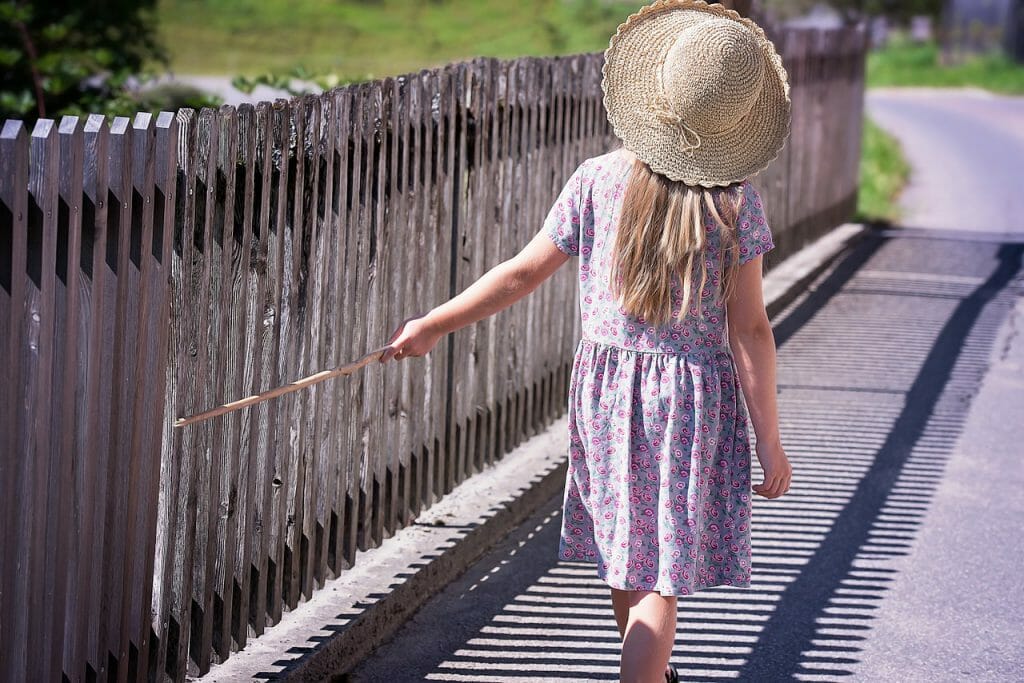 A kid walking outdoors with a hat on