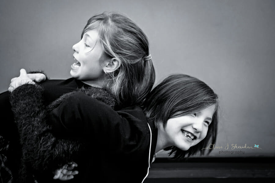 A black and white image of 2 girls playing and laughing