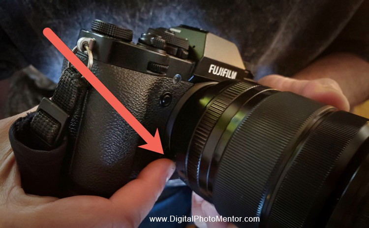 Lens release button on front of camera indicated by red arrow