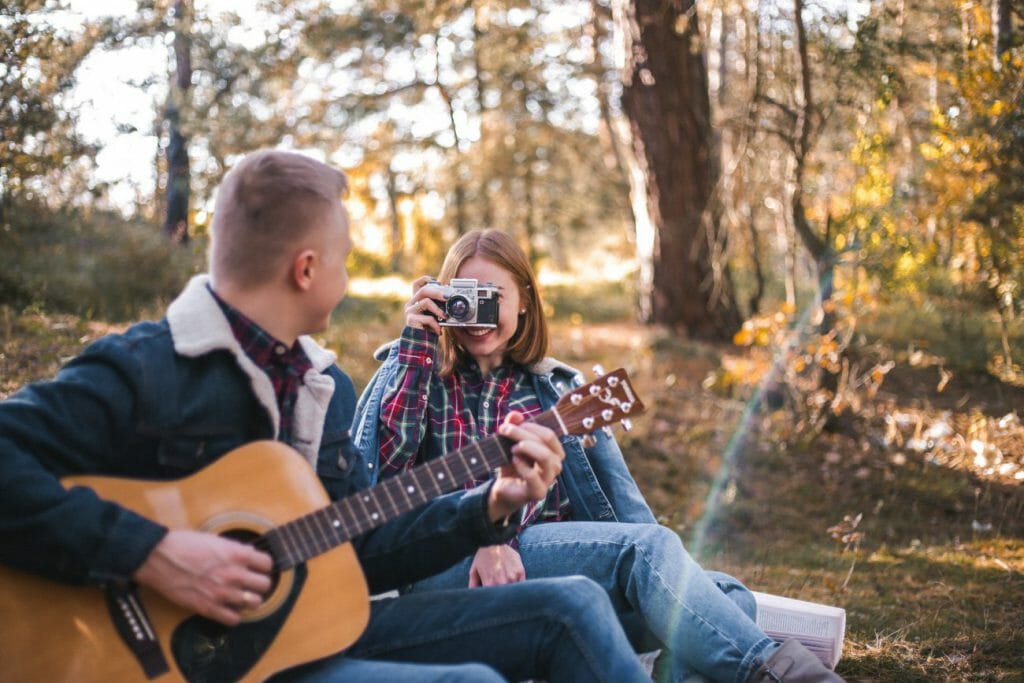 A couple posing during a family photography session with a guitar and camera.