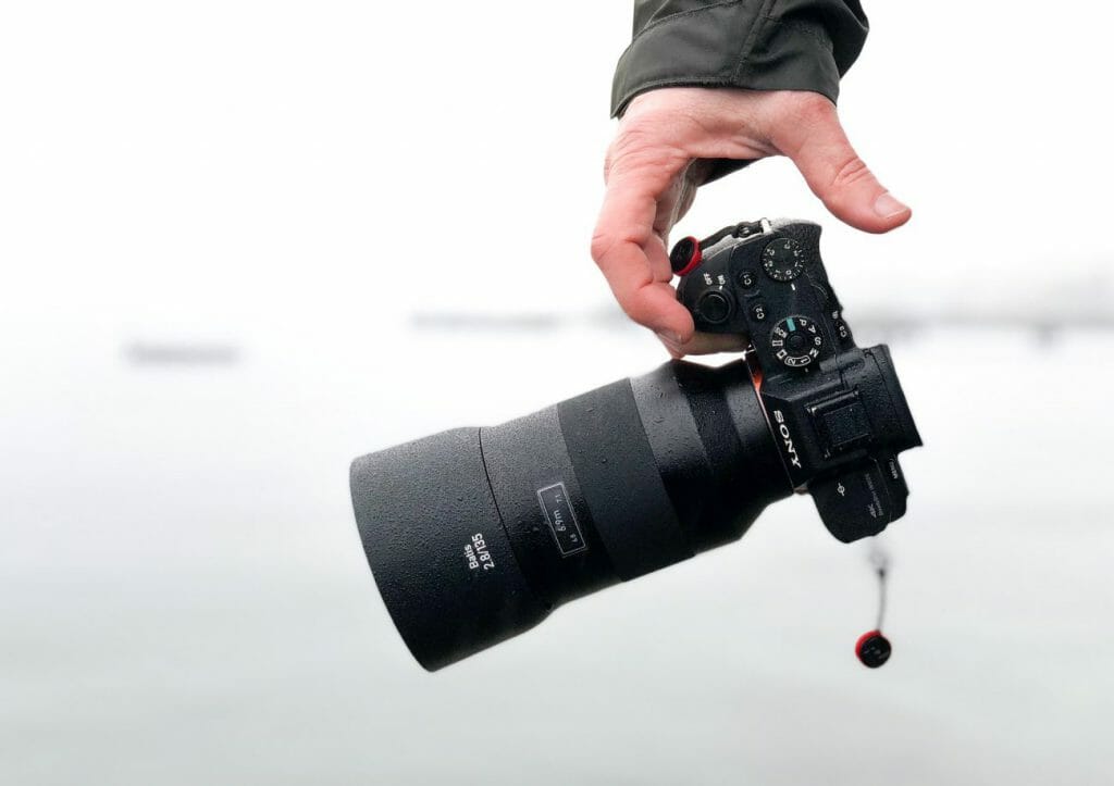 A man's hand holding a Sony camera - which is best in the full-frame vs crop sensor debate?