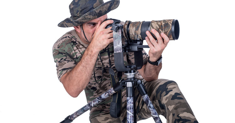 wildlife photographer dressed in camouflage with his camera so the birds dont see him