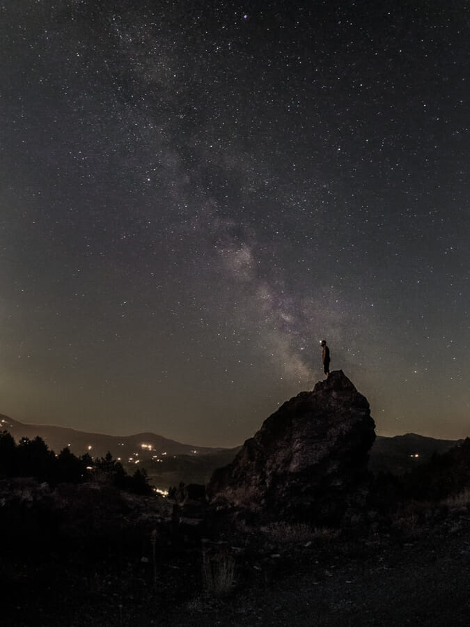 A man silhouetted against a starry night sky with the Milky Way visible