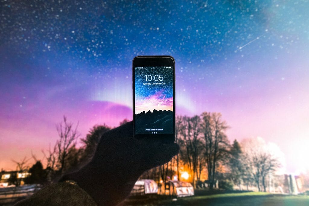 A person holds a smartphone up to a starry night to get a shot of the night sky