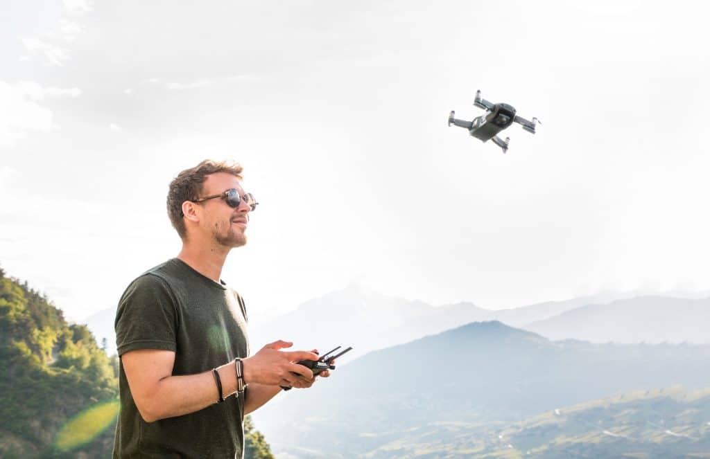 A mountain view with a man controlling his drone