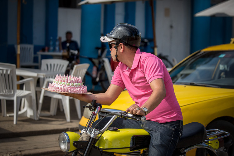 Street photograph of a man on a motorbike with a cake in Vinales Cuba