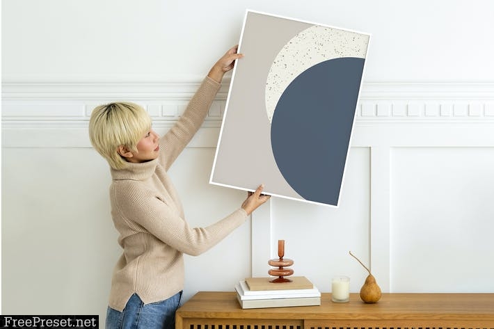 Woman hanging a photo frame on a white wall mockup